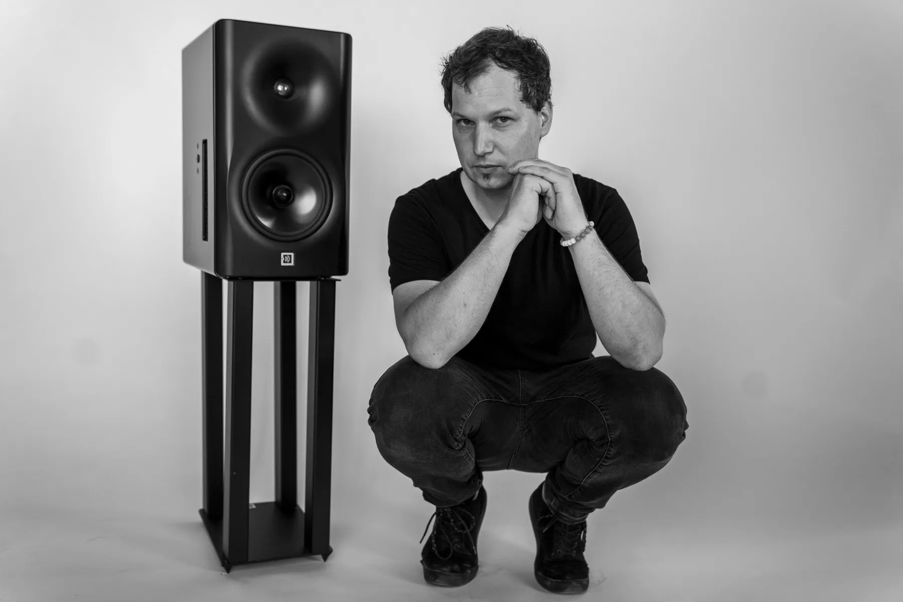 Márton Fenyvesi, crouching beside a studio monitor on a stand